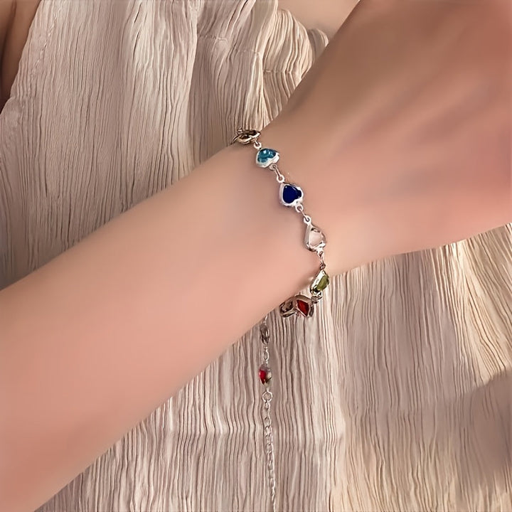 Pulsera de corazones multicolor con dijes pequeños y cadena dorada en la muñeca