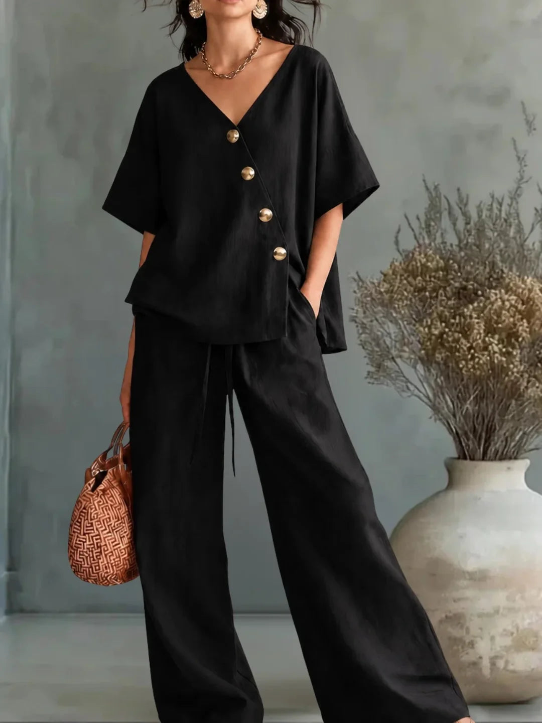 Conjunto negro: blusa con escote V y botones dorados, y pantalón ancho.
