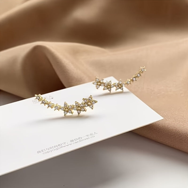 Pendientes florales de pedrería en tono oro, sobre tarjeta