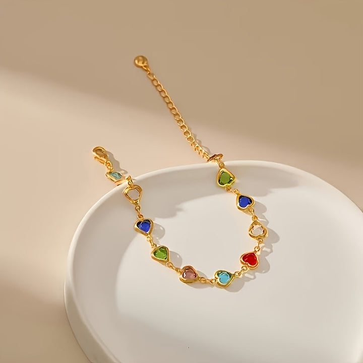 Pulsera de corazones multicolor con cadena dorada sobre plato blanco
