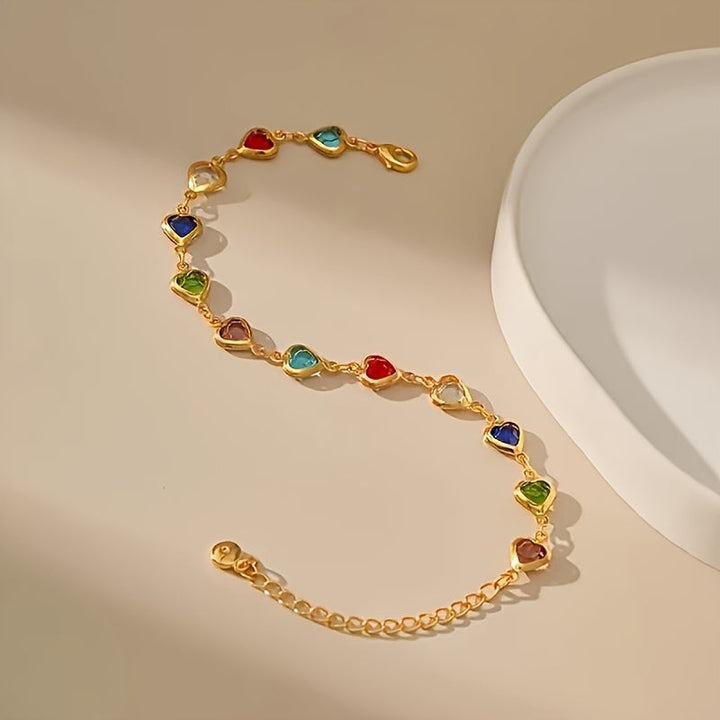 Pulsera de corazones multicolor con cadena dorada extendida sobre fondo claro