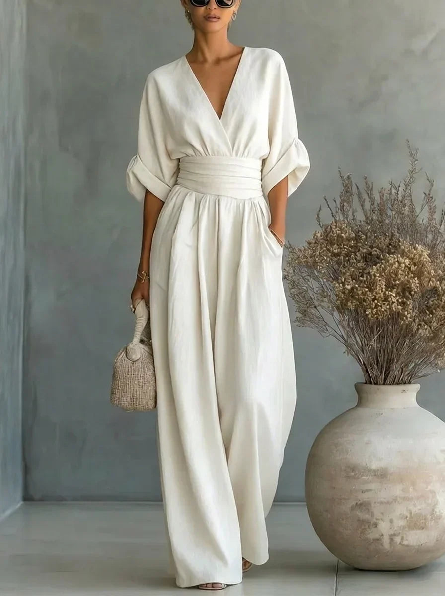 Vestido largo blanco con escote en V y cintura fruncida, mangas caídas y falda amplia.