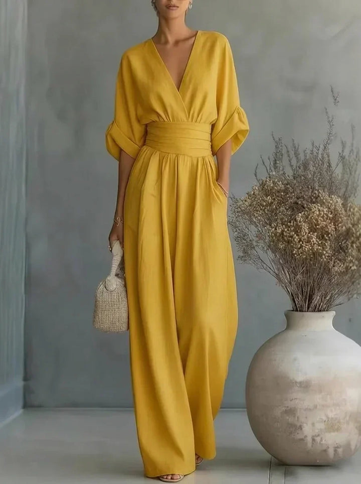 Vestido largo amarillo con escote en V y cintura fruncida, mangas caídas y falda amplia.