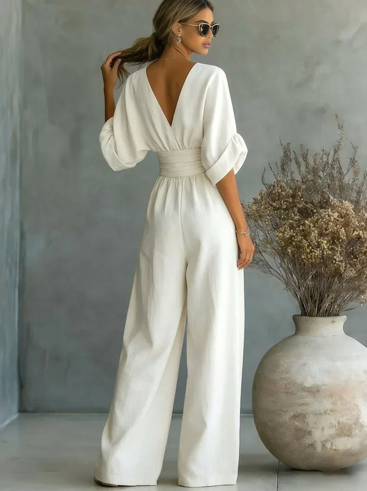 Mono blanco con escote en V cruzado, mangas amplias y pantalón ancho de cintura fruncida