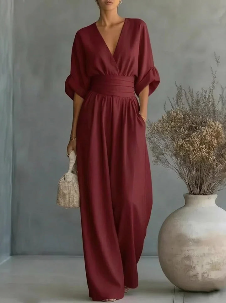 Vestido largo burdeos con escote en V y cintura fruncida, mangas caídas y falda amplia.